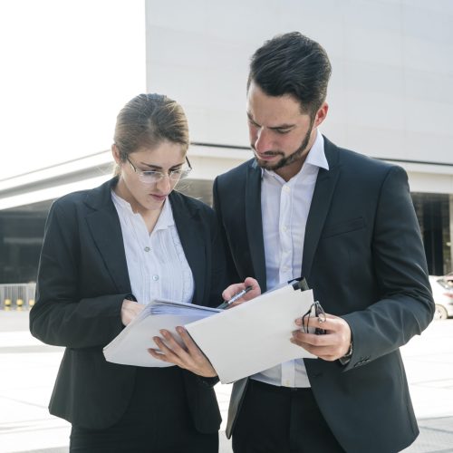 businessman-businesswoman-checking-documents-outdoors